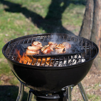 Scallops being cooked on griddle over charcoal grill.