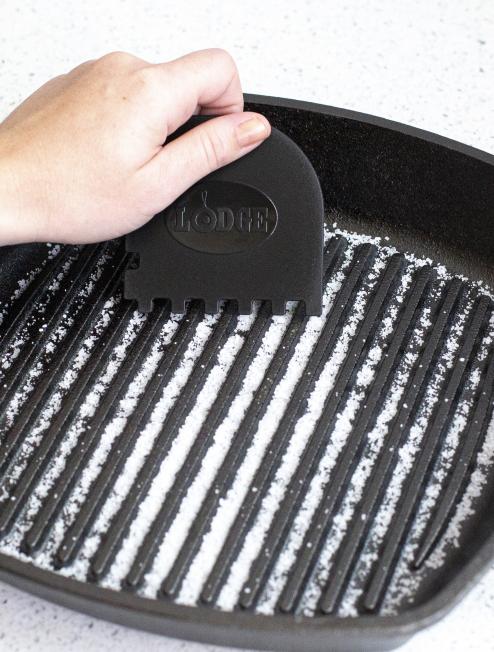 Someone using the black serrated scraper on their grill pan.
