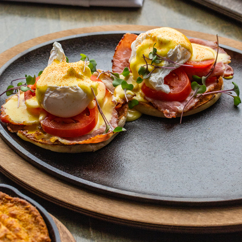 Eggs benedict on serving griddle with underliner.