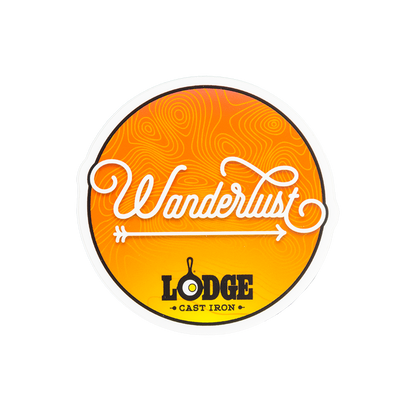 An orange sticker with Wanderlust written in a cursive font, an arrow, and Lodge logo.