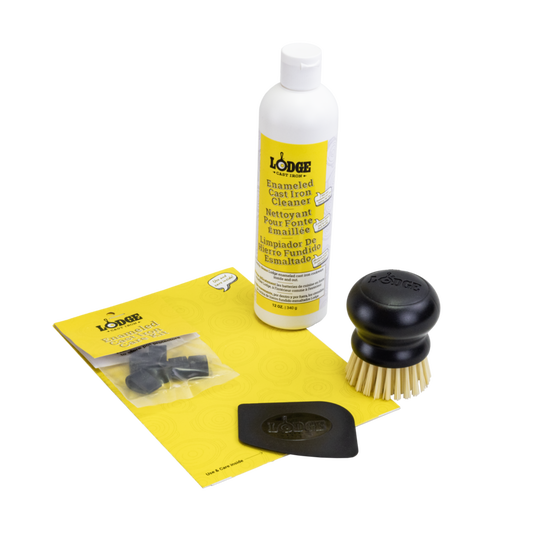 A collection of items for an enameled cast iron and stoneware care kit including a bottle of enamel cleaner, a black scrub brush with stiff bristles, a black pan scraper, and pot protectors.
