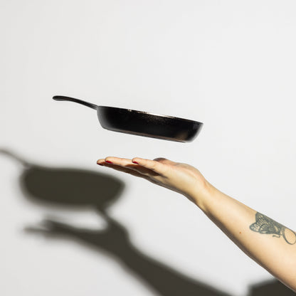 Someone tossing skillet in air, showing side profile and how product is light weight.