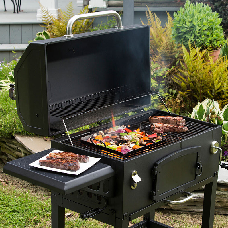 Veggies roasting on grill with basket while steak cooks nearby.