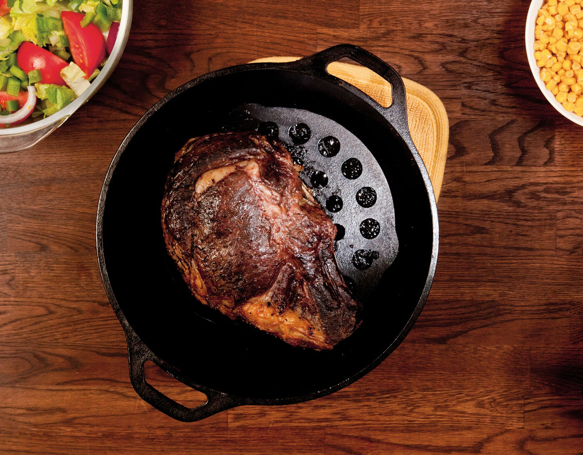 Prime rib roast freshly prepared with skillet and meat rack.