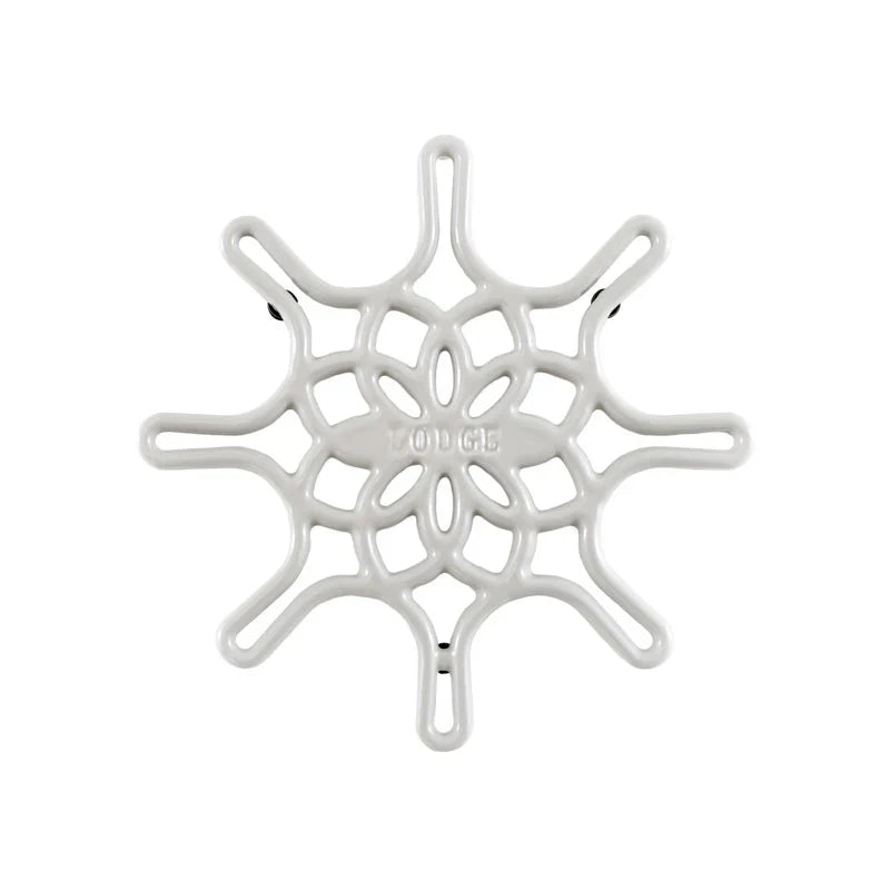 A white enameled cast iron trivet with a geometric snowflake-like pattern.