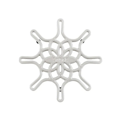 A white enameled cast iron trivet with a geometric snowflake-like pattern.