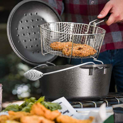 Someone taking out fried food from dutch oven using basket.