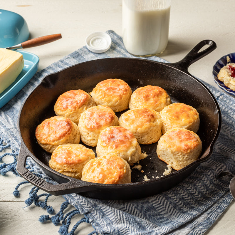 A skillet fully of freshly made and buttered biscuits.