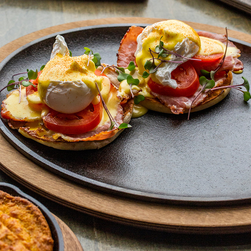 Fresh eggs benedict served on table with griddle.