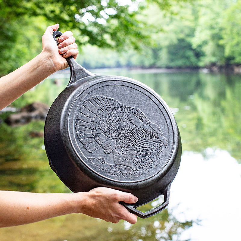 Someone holding skillet near river displaying embossed design on bottom of skillet.