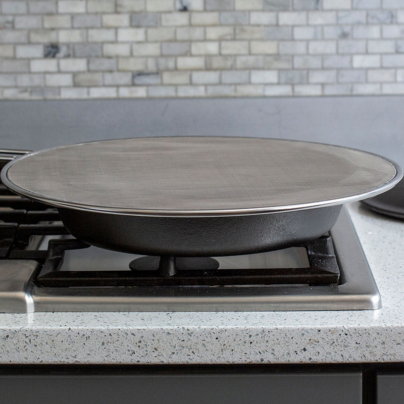 Someone using screen while cooking on stove with skillet.